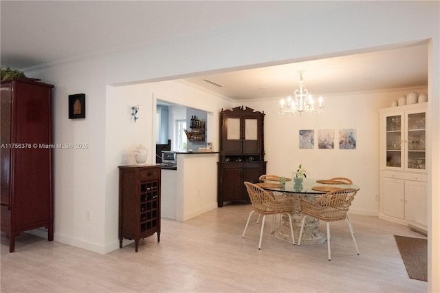 dining space featuring ornamental molding, light wood finished floors, baseboards, and an inviting chandelier