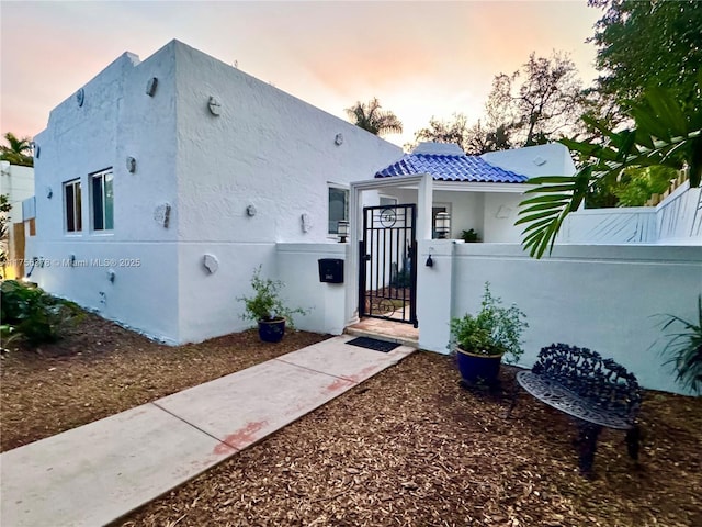 view of front of house with a fenced front yard, a gate, and stucco siding