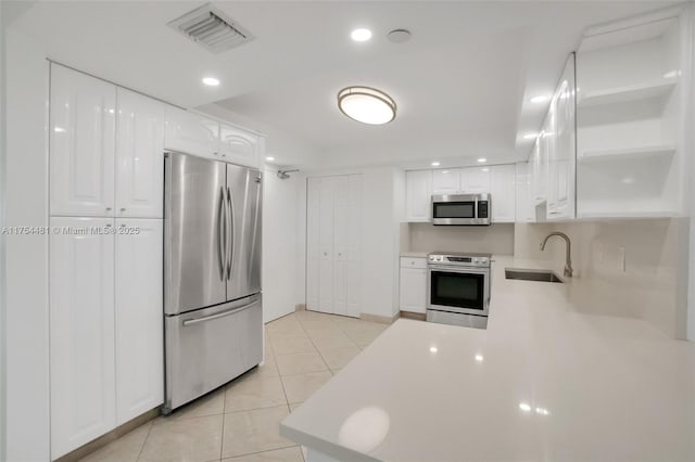 kitchen with light countertops, visible vents, appliances with stainless steel finishes, white cabinetry, and a sink