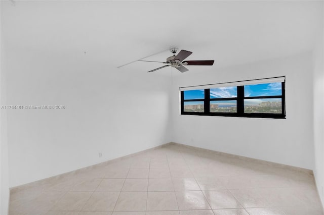 empty room featuring light tile patterned floors, ceiling fan, and baseboards