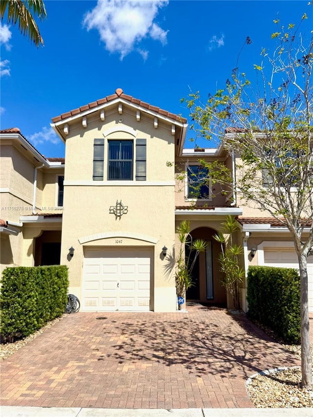 view of front of house with stucco siding, decorative driveway, a garage, a balcony, and a tiled roof