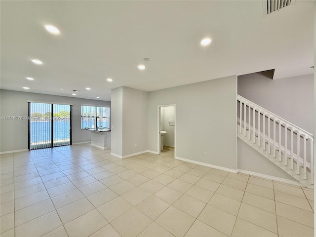 empty room with visible vents, recessed lighting, light tile patterned floors, baseboards, and stairs