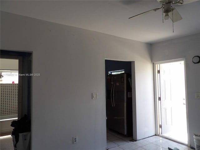 interior space featuring light tile patterned flooring, refrigerator with ice dispenser, and a ceiling fan