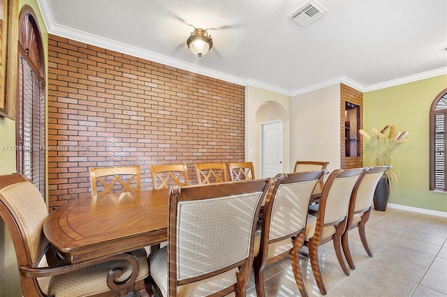 dining area featuring arched walkways, brick wall, visible vents, baseboards, and ornamental molding