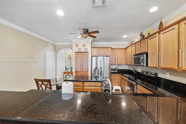 kitchen with arched walkways, crown molding, visible vents, appliances with stainless steel finishes, and a sink