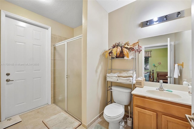 bathroom featuring a textured ceiling, tile patterned flooring, toilet, vanity, and a stall shower