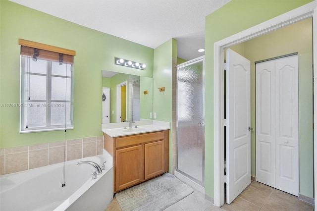 bathroom featuring a stall shower, tile patterned flooring, a garden tub, and vanity