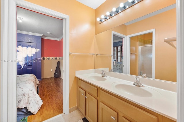 bathroom featuring crown molding, a sink, a shower stall, and double vanity