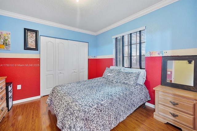 bedroom featuring baseboards, ornamental molding, wood finished floors, a textured ceiling, and a closet