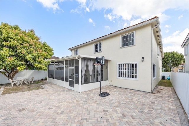 rear view of property with a sunroom, a fenced backyard, a patio area, and stucco siding