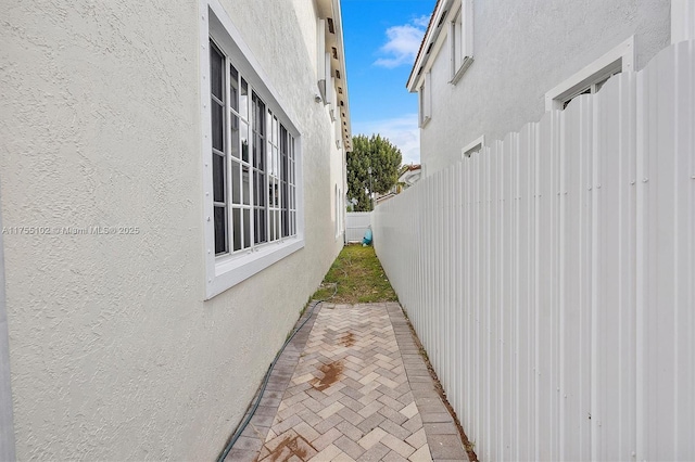 view of side of home with fence private yard, stucco siding, and a patio