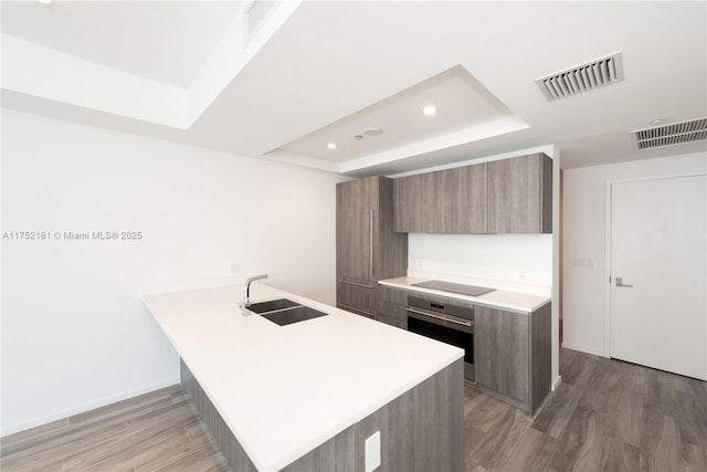 kitchen with visible vents, modern cabinets, a sink, and oven