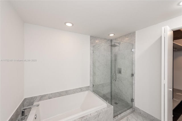 bathroom with a garden tub, a marble finish shower, and recessed lighting