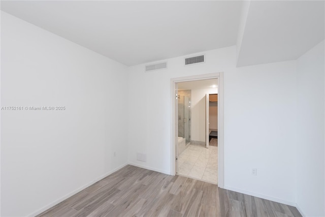 empty room featuring visible vents, baseboards, and wood finished floors