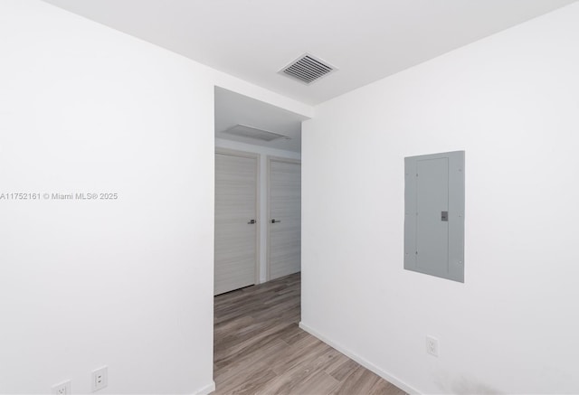 unfurnished room featuring baseboards, electric panel, visible vents, and wood finished floors