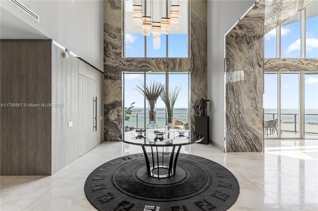 dining space with visible vents, marble finish floor, a water view, and a towering ceiling