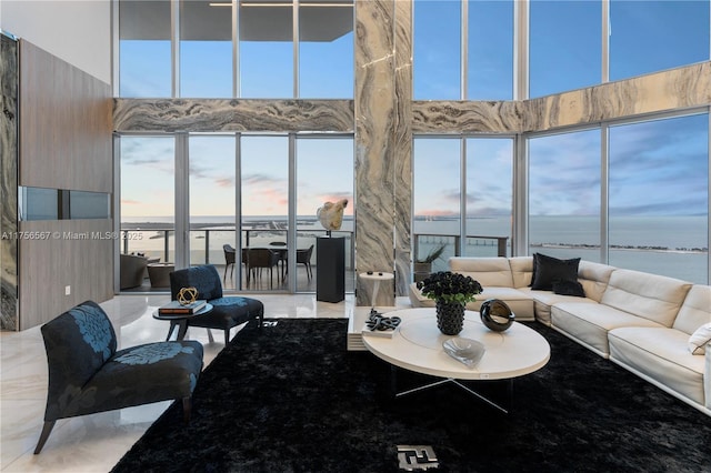 living area featuring marble finish floor, a water view, and a high ceiling