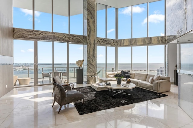 living area with a water view, marble finish floor, and a towering ceiling