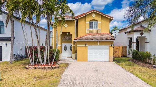 mediterranean / spanish house with decorative driveway, stucco siding, fence, a tiled roof, and a front lawn