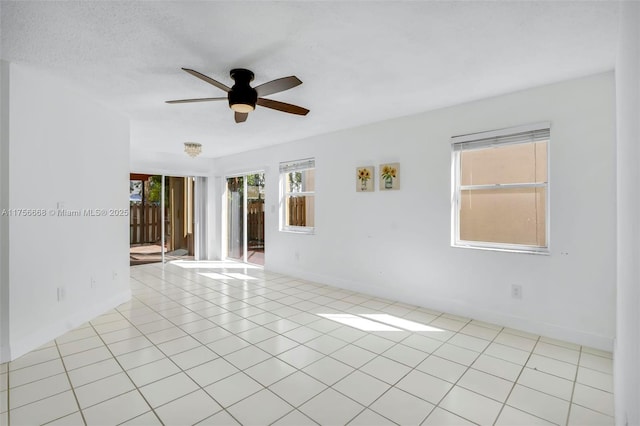 spare room featuring light tile patterned floors, ceiling fan, a textured ceiling, and baseboards