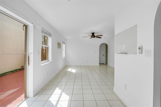 spare room featuring light tile patterned floors, ceiling fan, and arched walkways