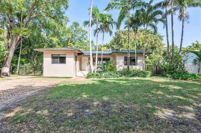 view of front of house featuring stucco siding, fence, metal roof, and a front yard