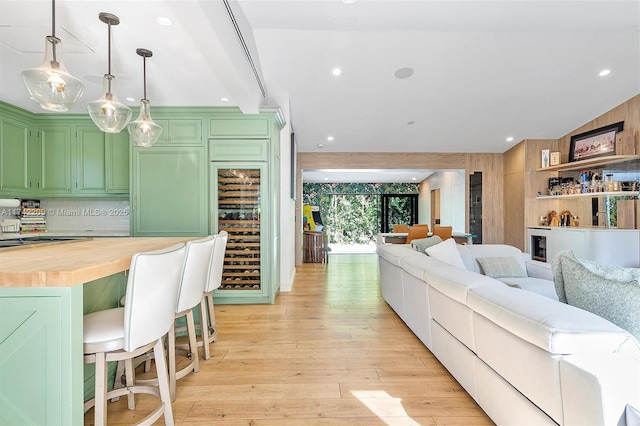 kitchen featuring light wood finished floors, wine cooler, wood counters, open floor plan, and green cabinets