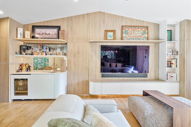 living room featuring built in features, wine cooler, indoor bar, lofted ceiling, and wood finished floors