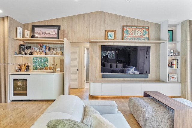 living area with lofted ceiling, built in features, indoor wet bar, and hardwood / wood-style floors