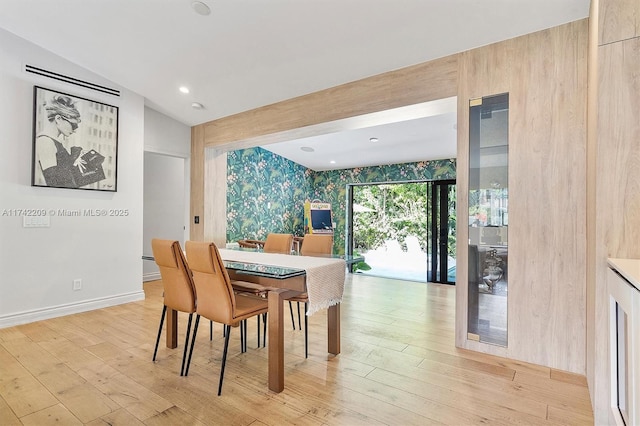 dining room with light wood-type flooring, baseboards, and vaulted ceiling