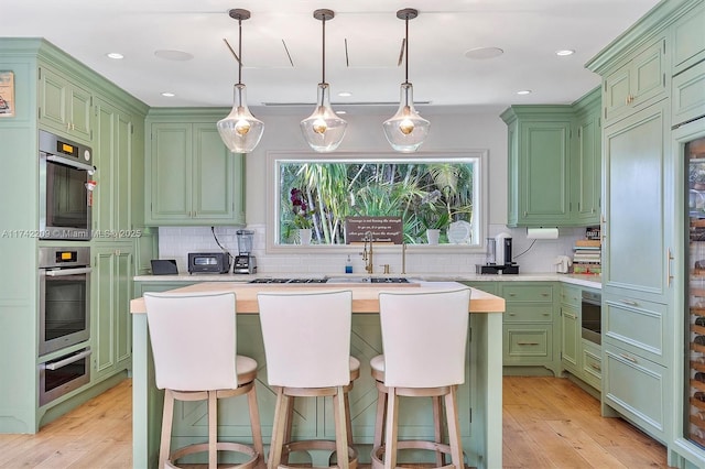 kitchen featuring a center island, light countertops, stainless steel double oven, green cabinets, and backsplash