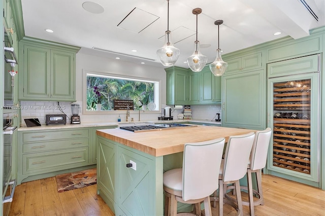 kitchen with light wood finished floors, a kitchen bar, wood counters, and green cabinetry