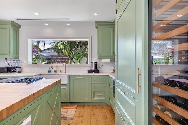 kitchen with a sink, a healthy amount of sunlight, light countertops, and green cabinetry