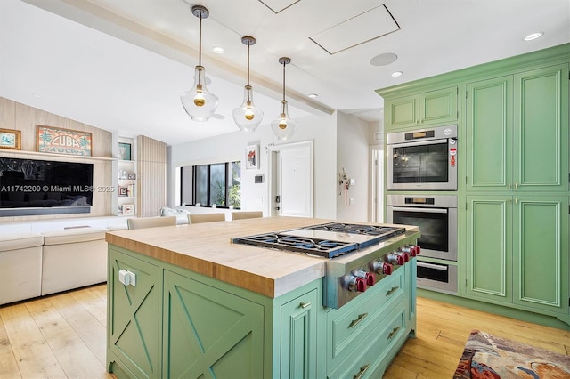 kitchen with stainless steel appliances, wood counters, open floor plan, light wood finished floors, and green cabinetry