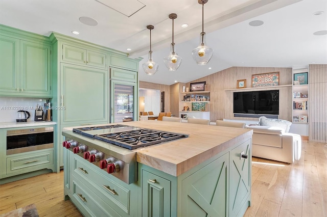 kitchen with stainless steel gas cooktop, butcher block countertops, lofted ceiling, and green cabinetry