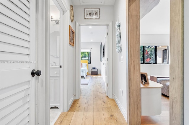 corridor with light wood-style flooring and baseboards