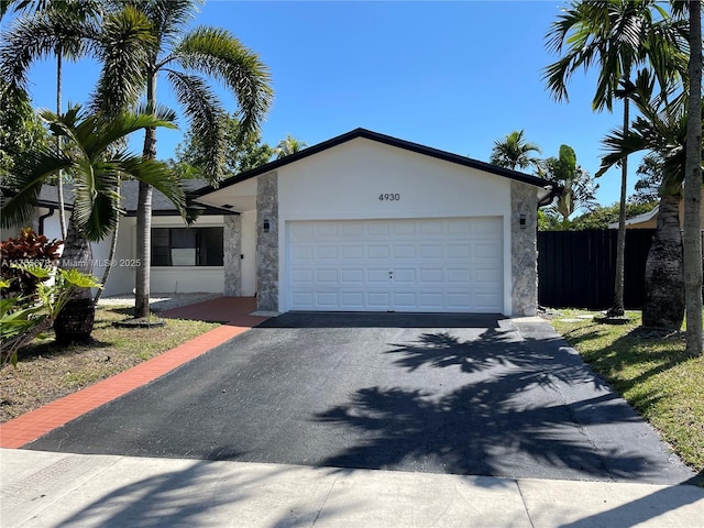 view of front of home with a garage, fence, aphalt driveway, and stucco siding