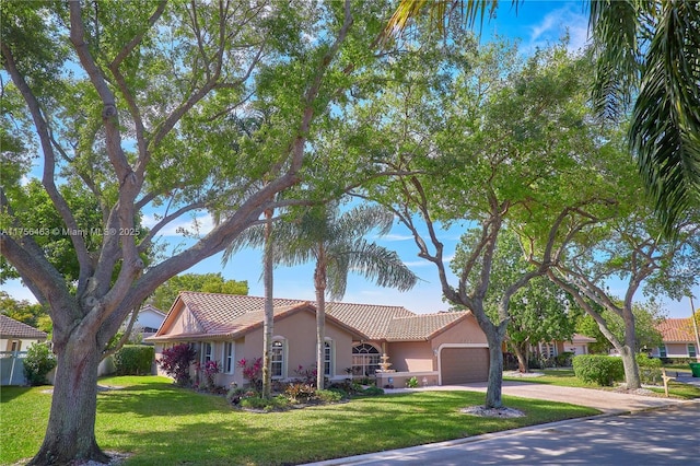 view of front of home with a garage, driveway, a tiled roof, a front yard, and stucco siding