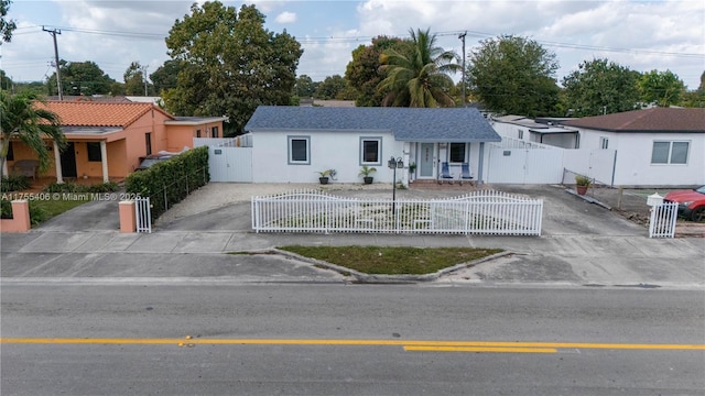 view of front of house featuring concrete driveway, a fenced front yard, and a gate