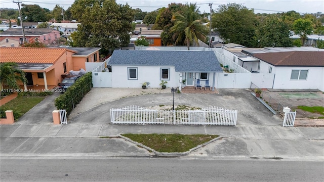 view of front of home featuring a fenced front yard, driveway, a residential view, a gate, and stucco siding