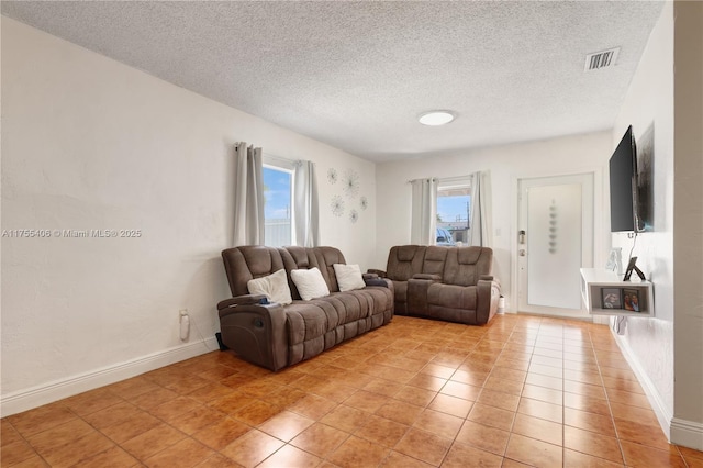 living room with a textured ceiling, visible vents, and a wealth of natural light