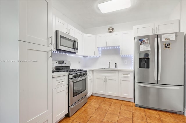 kitchen featuring a sink, stainless steel appliances, light countertops, and white cabinets