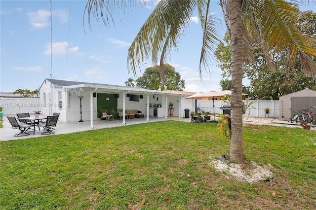 rear view of house with an outbuilding, a yard, a storage shed, a patio area, and a fenced backyard