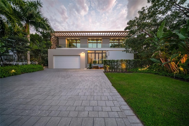 view of front of home featuring a garage, a front lawn, decorative driveway, and stucco siding