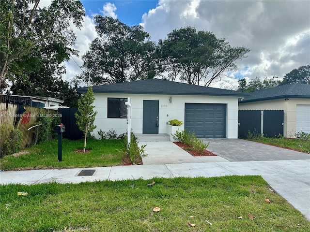 ranch-style house with a garage, decorative driveway, a front yard, and fence