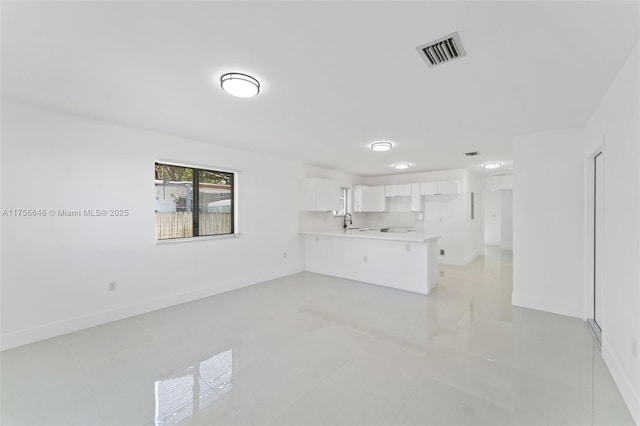 unfurnished living room featuring baseboards, visible vents, and a sink