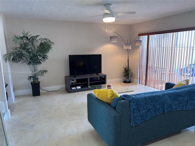 living area with baseboards, a textured ceiling, and ceiling fan