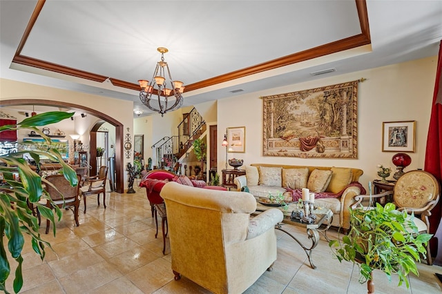 living area featuring visible vents, a tray ceiling, arched walkways, and a notable chandelier