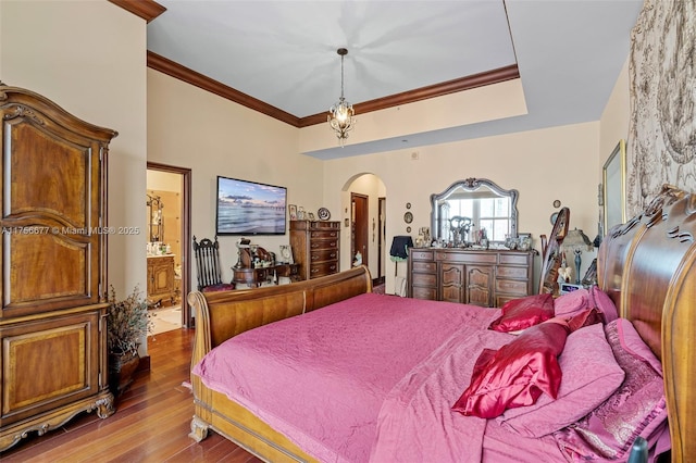 bedroom with crown molding, connected bathroom, arched walkways, and wood finished floors