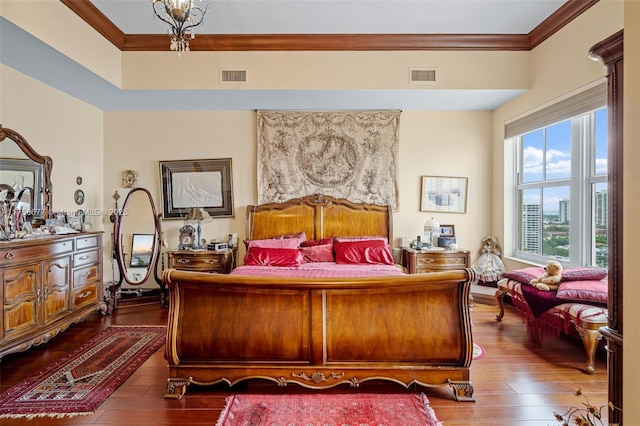 bedroom with dark wood-type flooring, visible vents, and ornamental molding